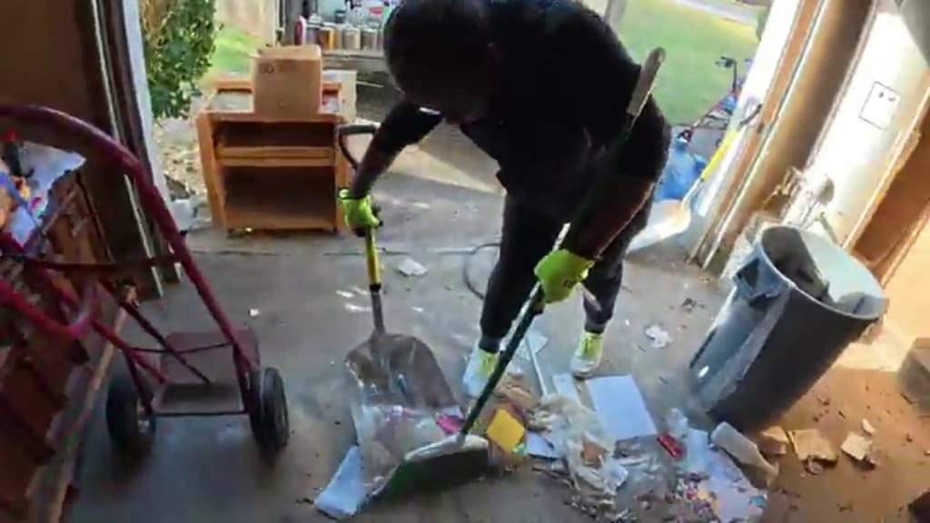 Crew member sweeping the garage floor at the end of a cleanout