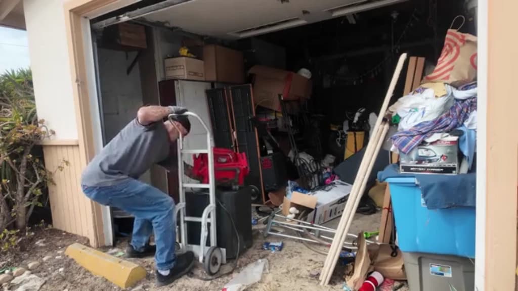 Hauler moving a heavy household appliance out of a garage on a hand truck